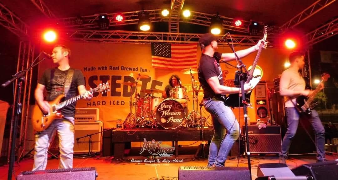Greg Warren Band high-energy rock performance with American flag and stage lights